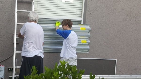 Greg Gatscher, left, and his son, Evan, prepare the house for Hurricane Irma. Little did they know these metal shutters would later become a cooktop.