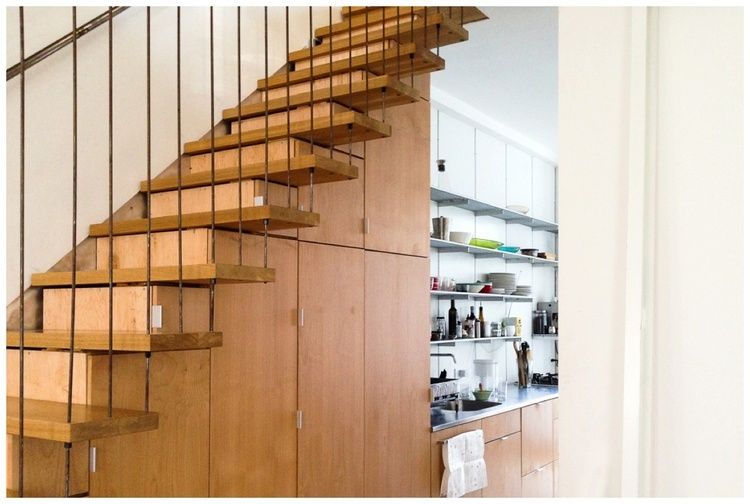 Space under the stairwell doubles as seamless custom cabinetry for kitchen storage